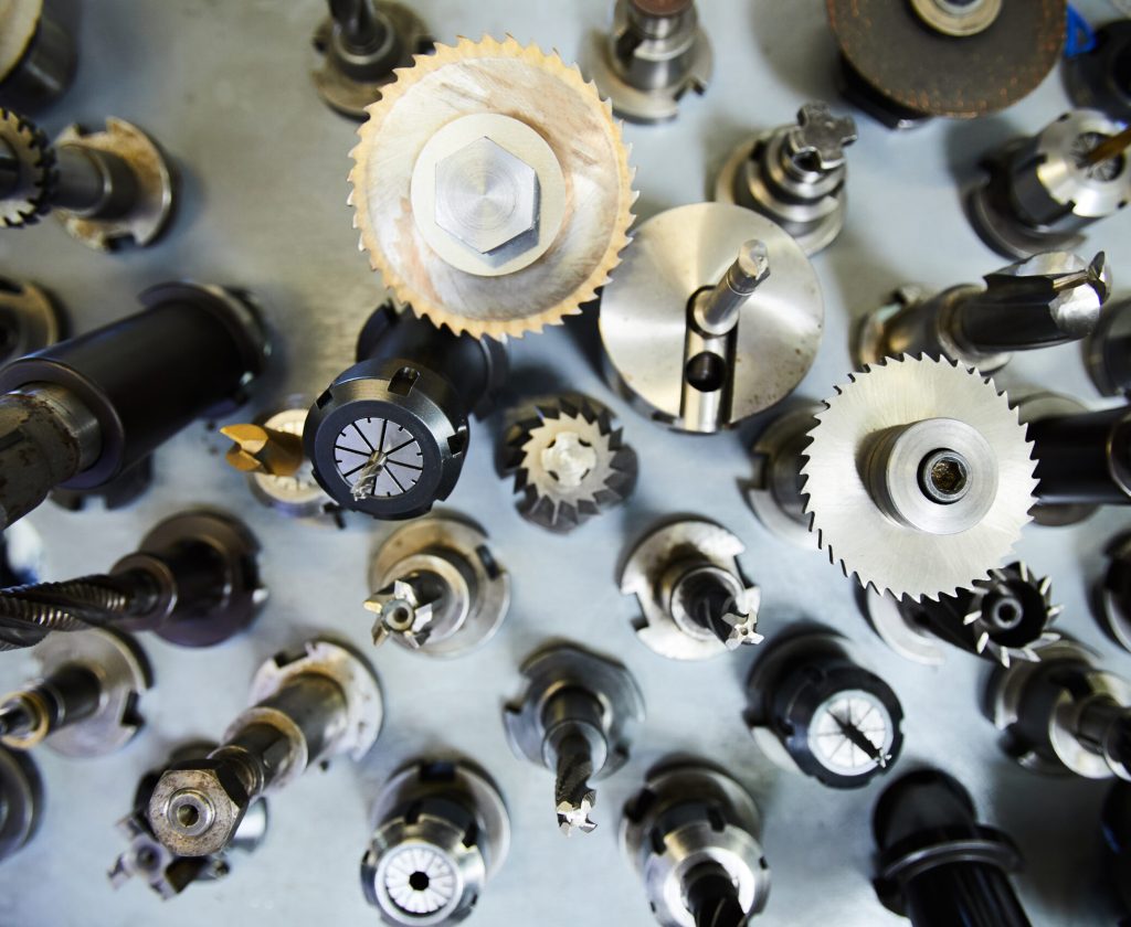 High angle view of metal milling cutters with various bits on steel table